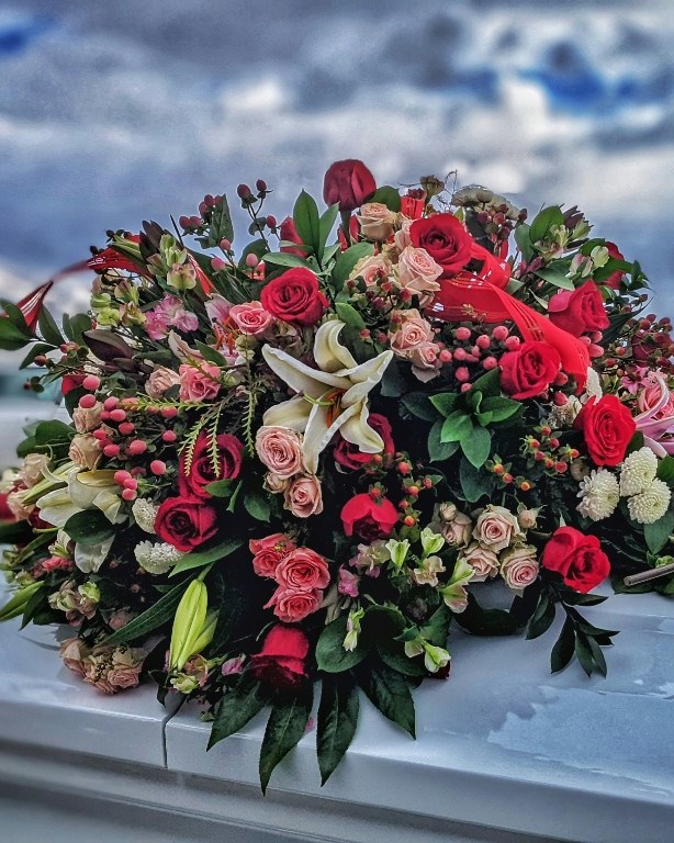 Funeral spray of red and pink roses with white lilies ready for memorial flower preservation